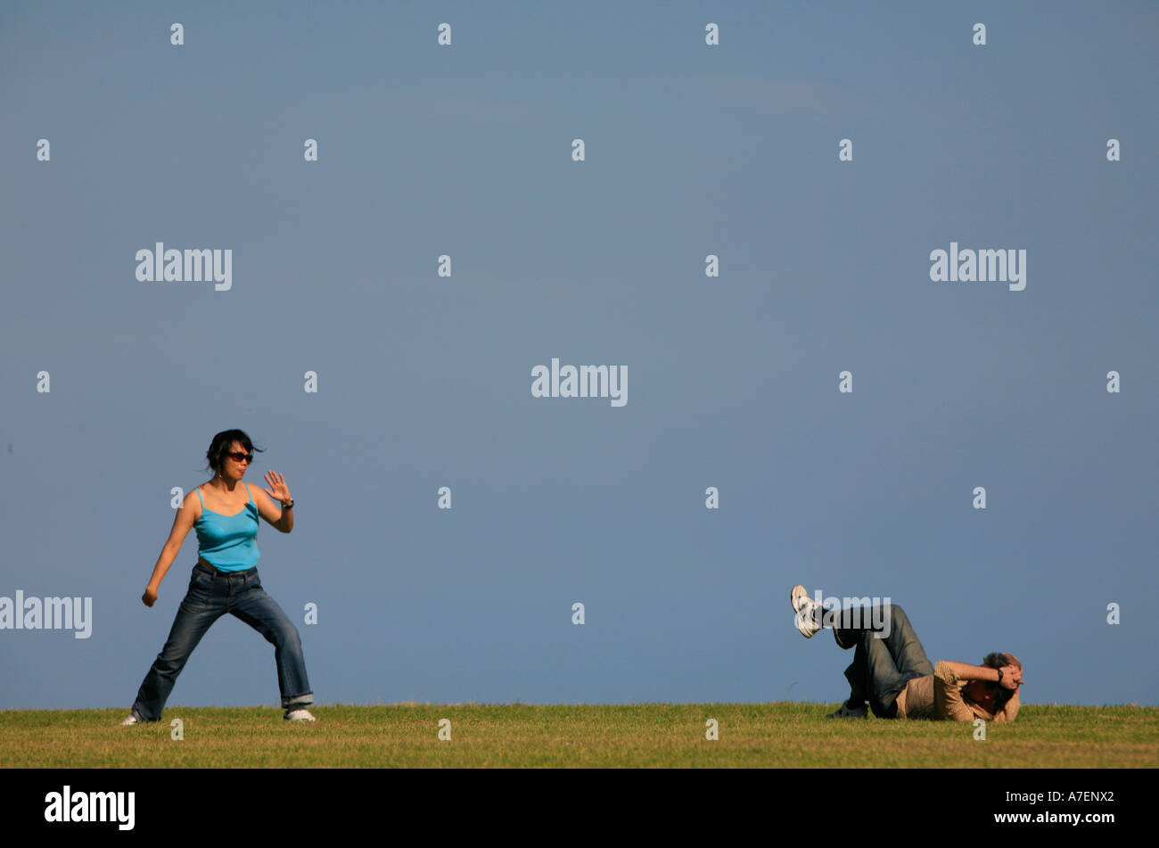 Una donna non Tai Chi mentre il suo partner si stende su erba a guardare Foto Stock