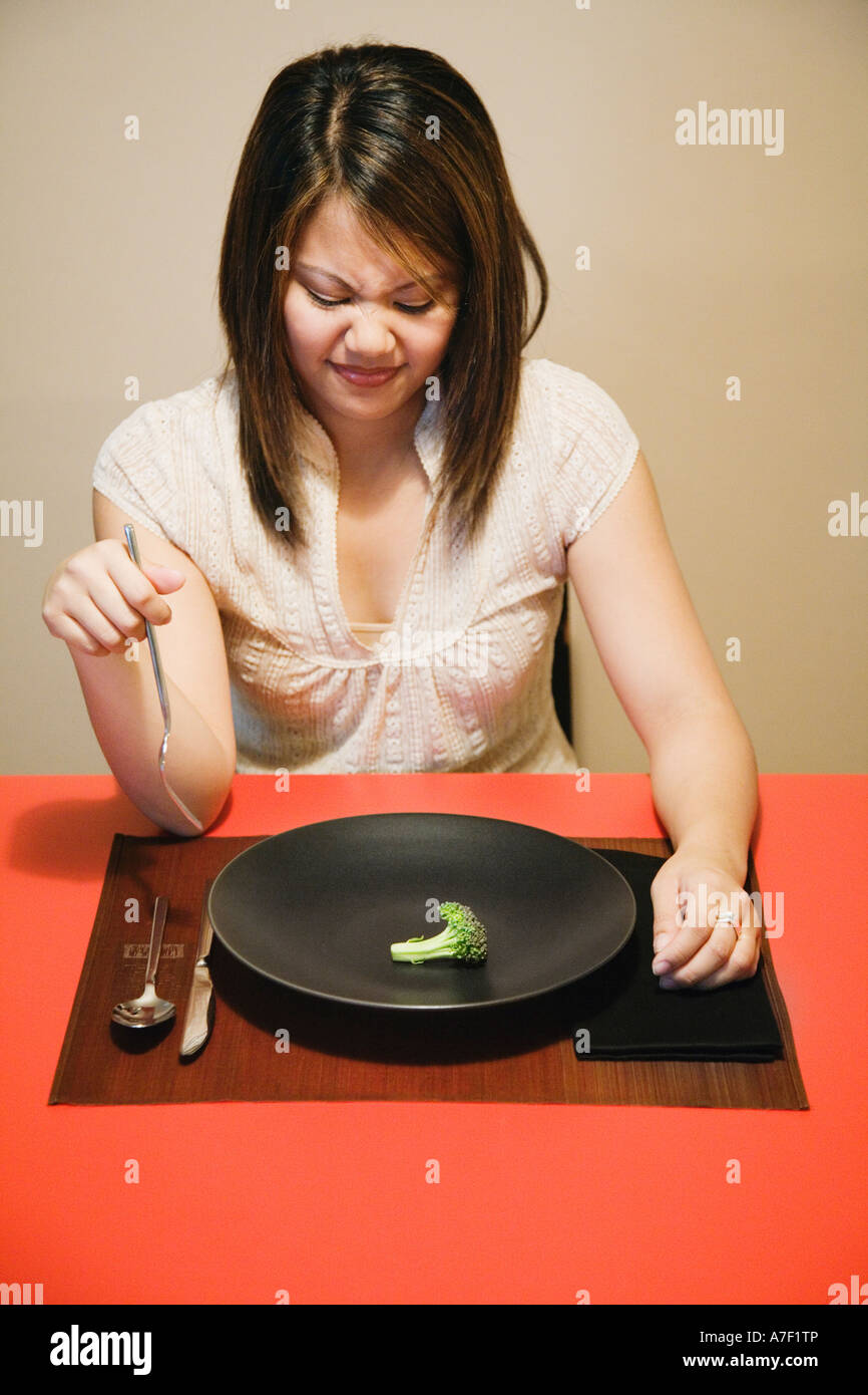 Donna asiatica con un pezzo di broccoli su piastra Foto Stock