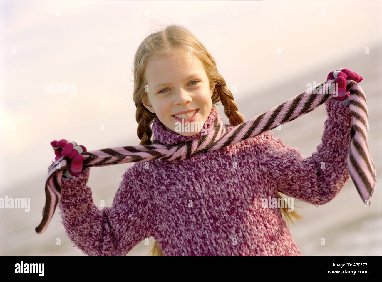Giovane ragazza che gioca con la sciarpa sulla spiaggia e sorridente in telecamera Foto Stock