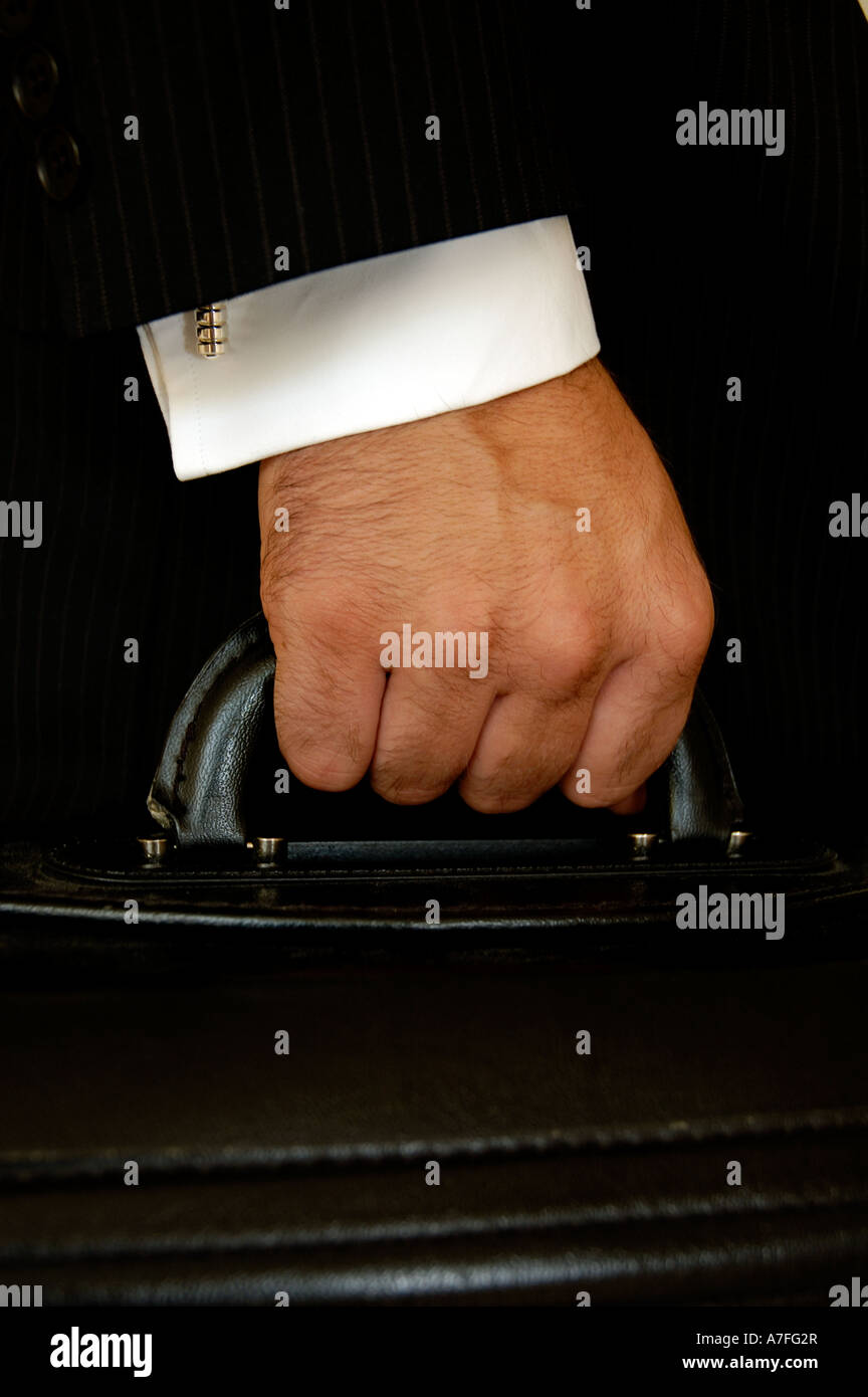 Close up di un imprenditore il mano che tiene una valigetta indossa una tuta e camicia con gemelli Foto Stock