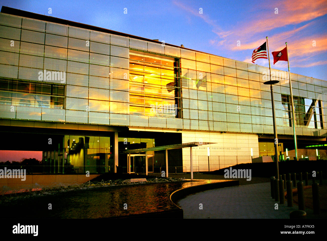 Un bel tramonto e gli Stati Uniti e Arkansas bandiere riflettere nel vetro del William Jefferson Clinton Library Foto Stock