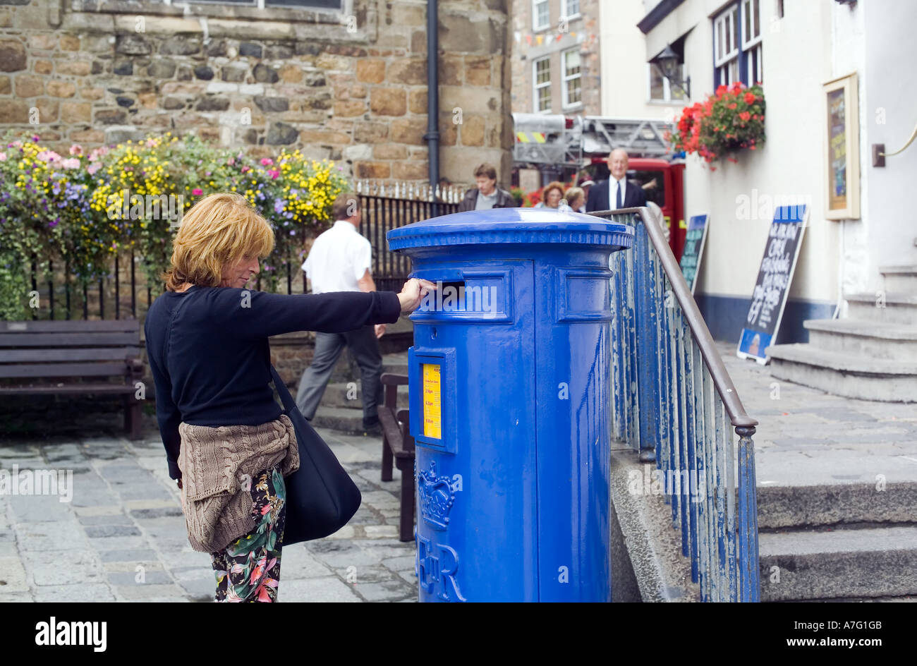 SIG. DONNA CHE INVIA POSTA IN UNA CASSETTA DELLE LETTERE DEL PILASTRO BLU PORTO DI ST-PETER GUERNSEY, ISOLE DEL CANALE DELLA GRAN BRETAGNA Foto Stock