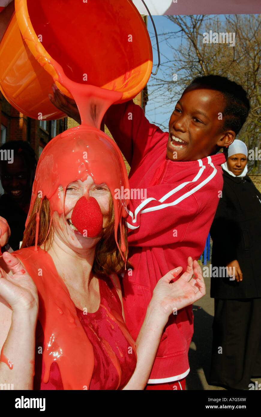 Scolaro gunging il suo insegnante sul naso rosso al giorno per il sollievo comico, Londra, Regno Unito. Foto Stock