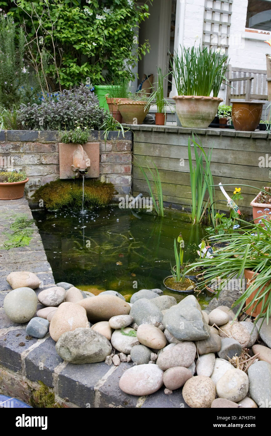 Piccolo rialzato del laghetto in giardino con pareti in mattoni e fontana  CHELTENHAM REGNO UNITO Foto stock - Alamy