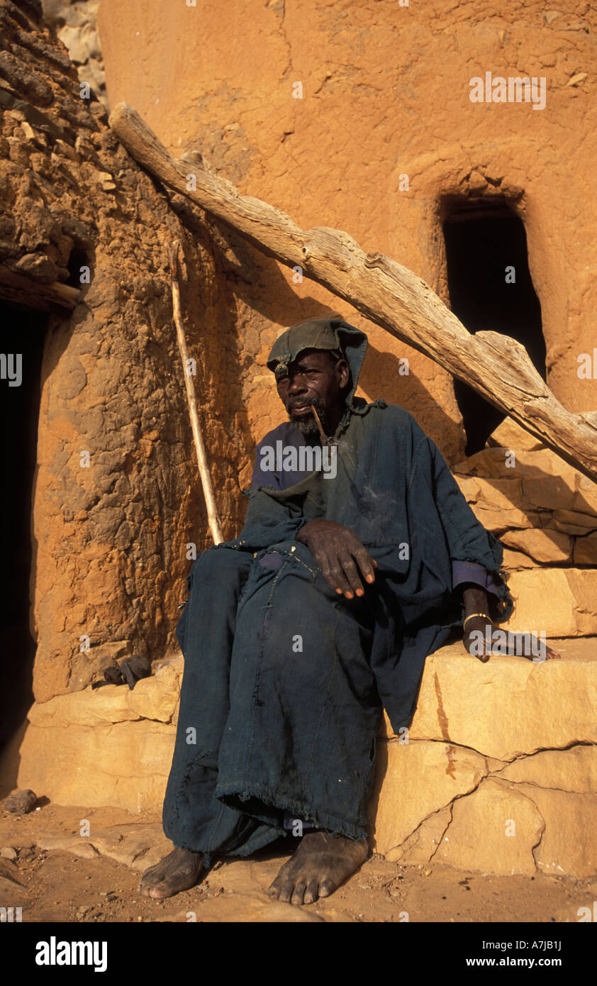 Hogon, leader spirituale di fumare un tubo nella sua scogliera scolpita home, Ende village, Paese Dogon del Mali Foto Stock