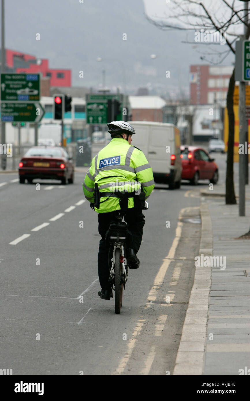 PSNI funzionario di polizia in mountain bike guarda al lato di andare fino a Victoria Street su il giorno di San Patrizio Belfast Irlanda del Nord Foto Stock