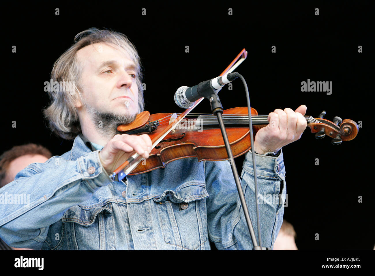 Willie Drennan Pasturatore musicista sul palco con violino fiddle e microfono indossando giacca denim durante il concerto per il giorno di San Patrizio Foto Stock