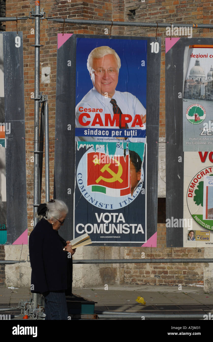 Unione elezioni locali in Italia locali disinteressato donna anziana ignora posters e legge prenota Foto Stock