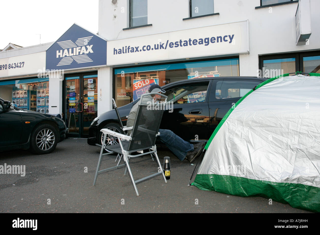 gruppo di buyer della prima volta accamparono fuori di un'agenzia immobiliare nell'irlanda del nord con le automobili e la tenda in attesa di rilascio durante la bolla di proprietà del 2007 Foto Stock