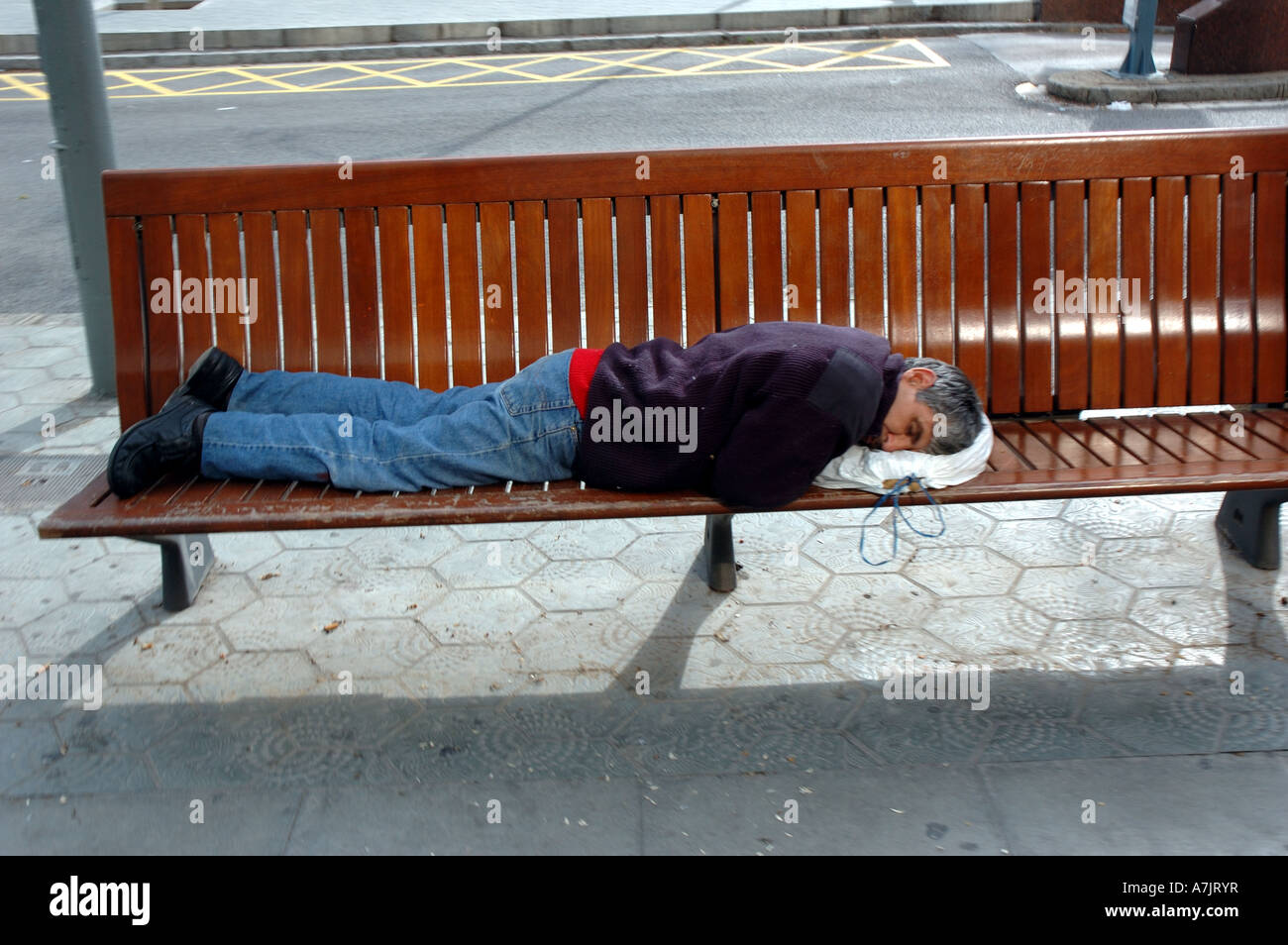 L'uomo addormentato sul sedile pubblico a Barcellona, in Catalogna, Spagna Foto Stock