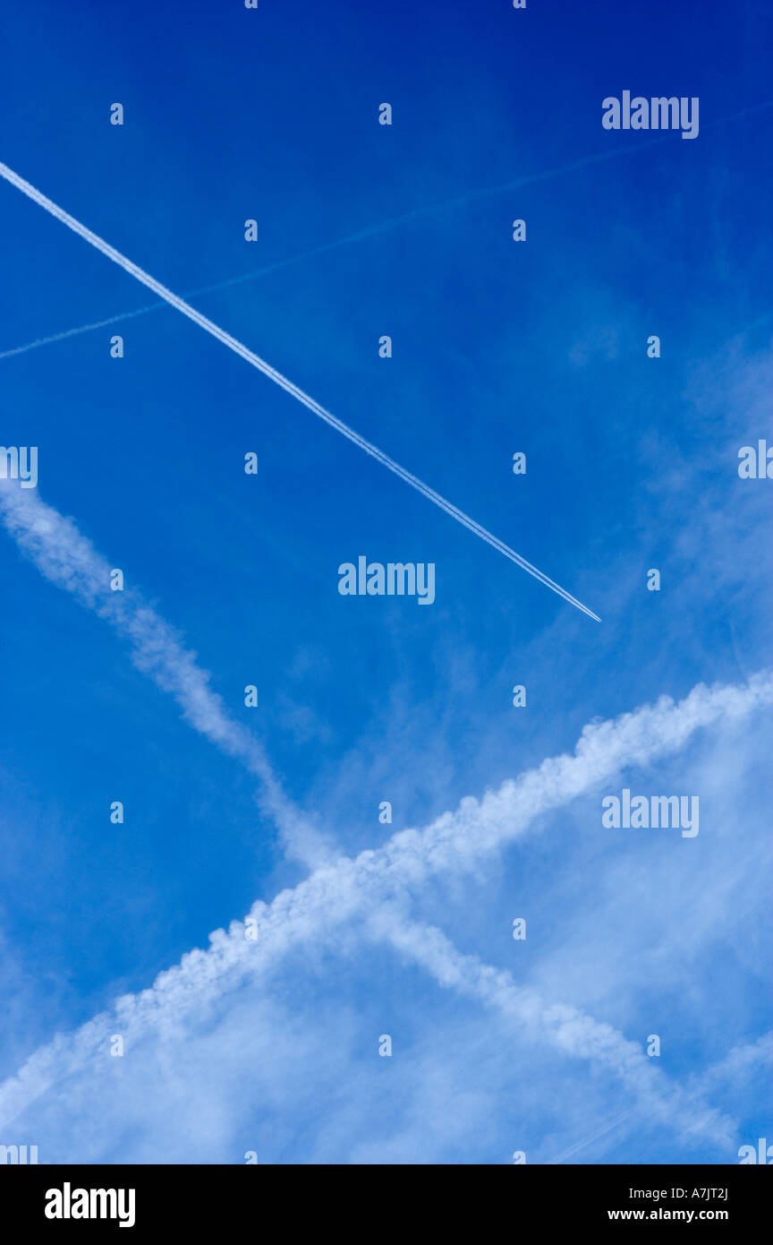 Velivoli a getto di vapore attraversando sentieri di cielo blu chiaro Foto Stock
