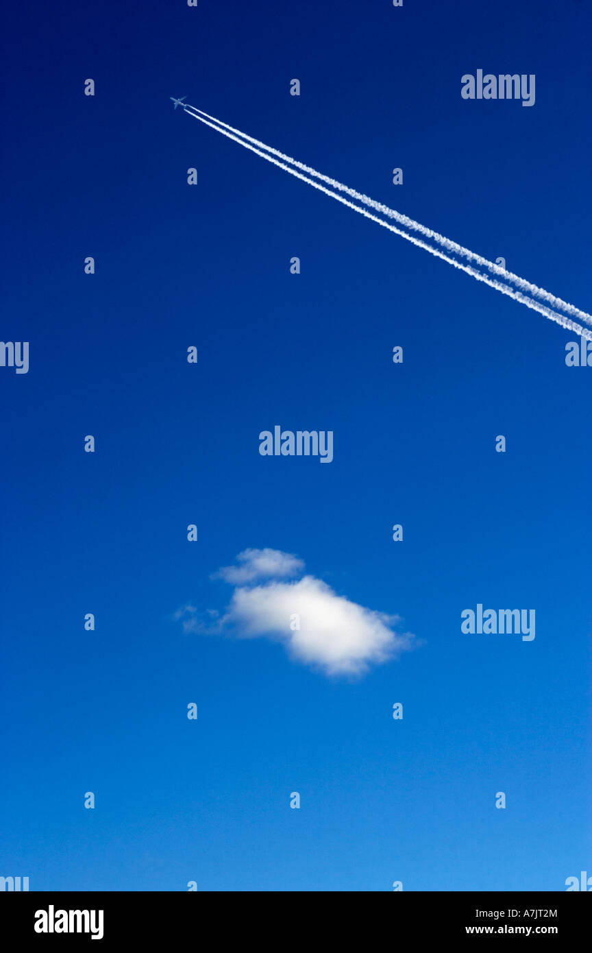 Singola nuvola bianca e di un aeromobile jet sentiero di scarico nel cielo blu chiaro Foto Stock