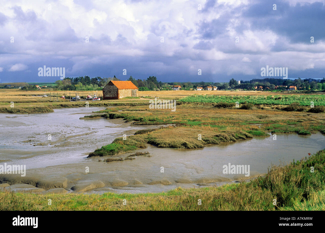 Thornham, Norfolk, Carbone granaio, creek e il villaggio sulla costa nord occidentale, saline, East Anglia, England, Regno Unito, nuvole di tempesta Foto Stock