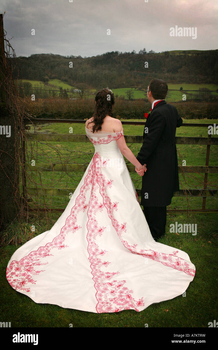 Sposa che indossa un bianco tradizionale abito da sposa con treno lungo e  di colore rosso brillante decorazione di pizzo guarda a distanza con il  marito Foto stock - Alamy