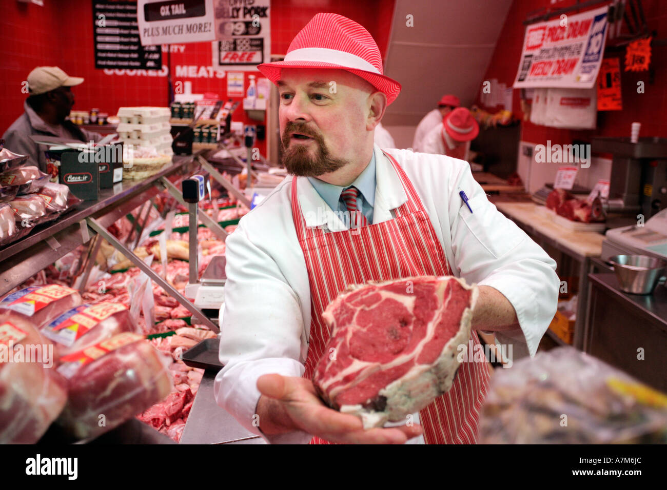 Un macellaio mostra un taglio di carne per un cliente nel suo negozio a Birmingham REGNO UNITO Foto Stock