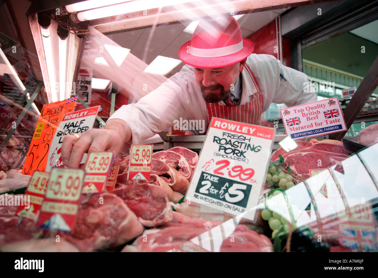Un macellaio organizza il suo display di carne nella finestra del suo negozio a Birmingham REGNO UNITO Foto Stock