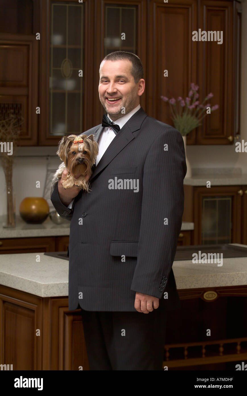 Vista laterale di uomo vestito con una tuta e tenendo premuto lap dog Foto Stock