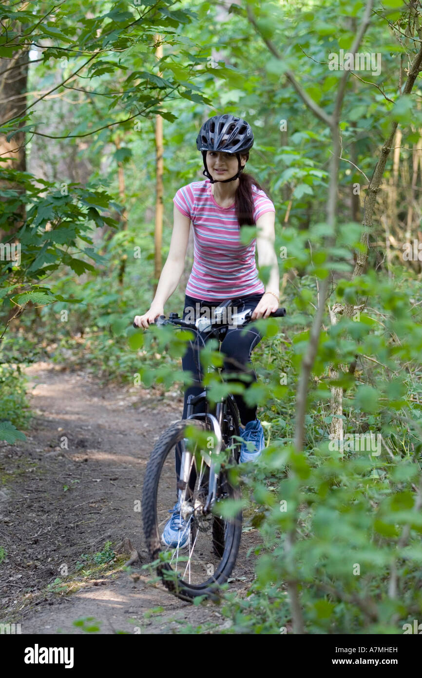 Ragazza sua equitazione mountain bike lungo un sentiero forestale Foto Stock