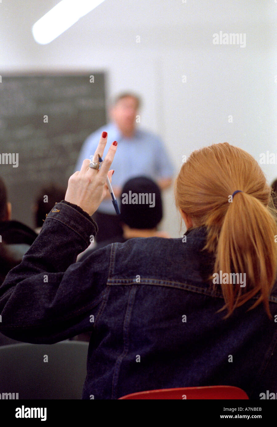 Guardando oltre la spalla di uno studente come Lei alza il canto in classe Foto Stock