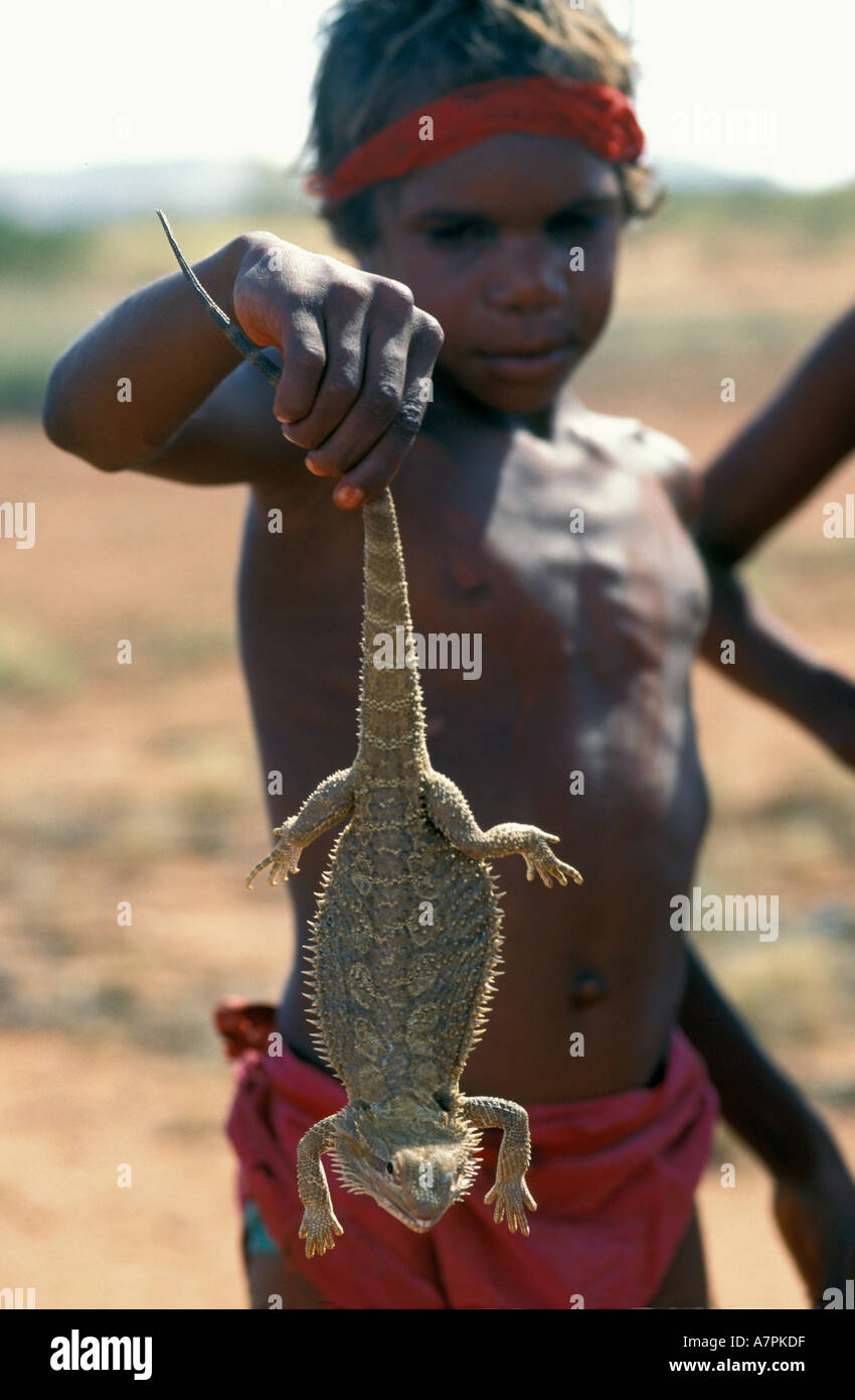 Giovane ragazzo aborigeno detiene una lucertola pungenti catturati nel deserto remoto Patria a sud di Alice Springs Australia centrale Foto Stock