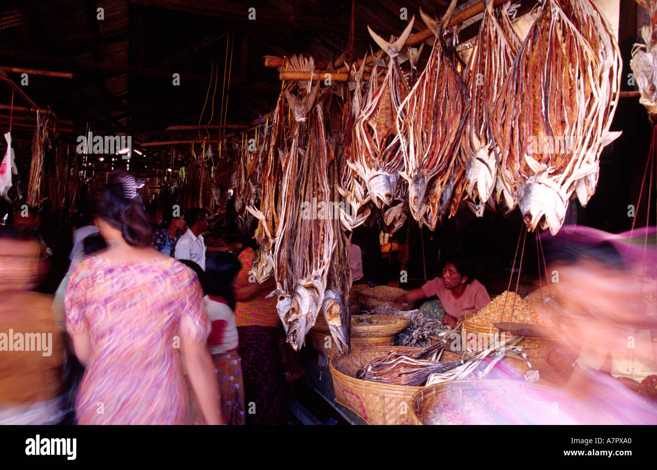 Gli acquirenti e i negozianti in Sittwe mercato con pesci secchi appesi al soffitto Foto Stock