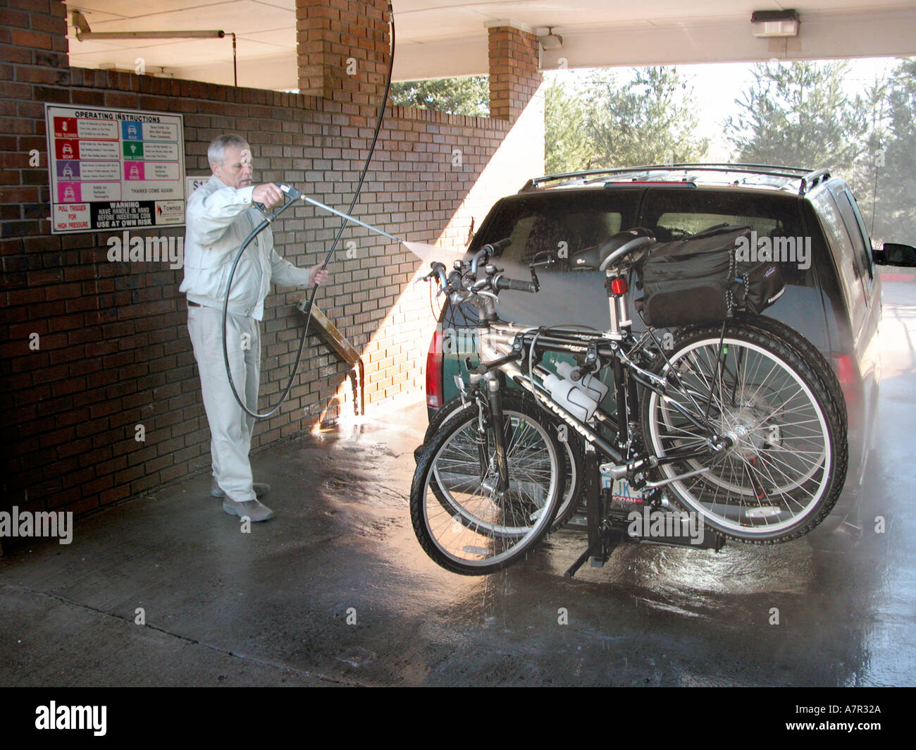 Senior adulto bianco uomo SUV di lavaggio in lavaggio auto con la bici sul rack sul retro Foto Stock