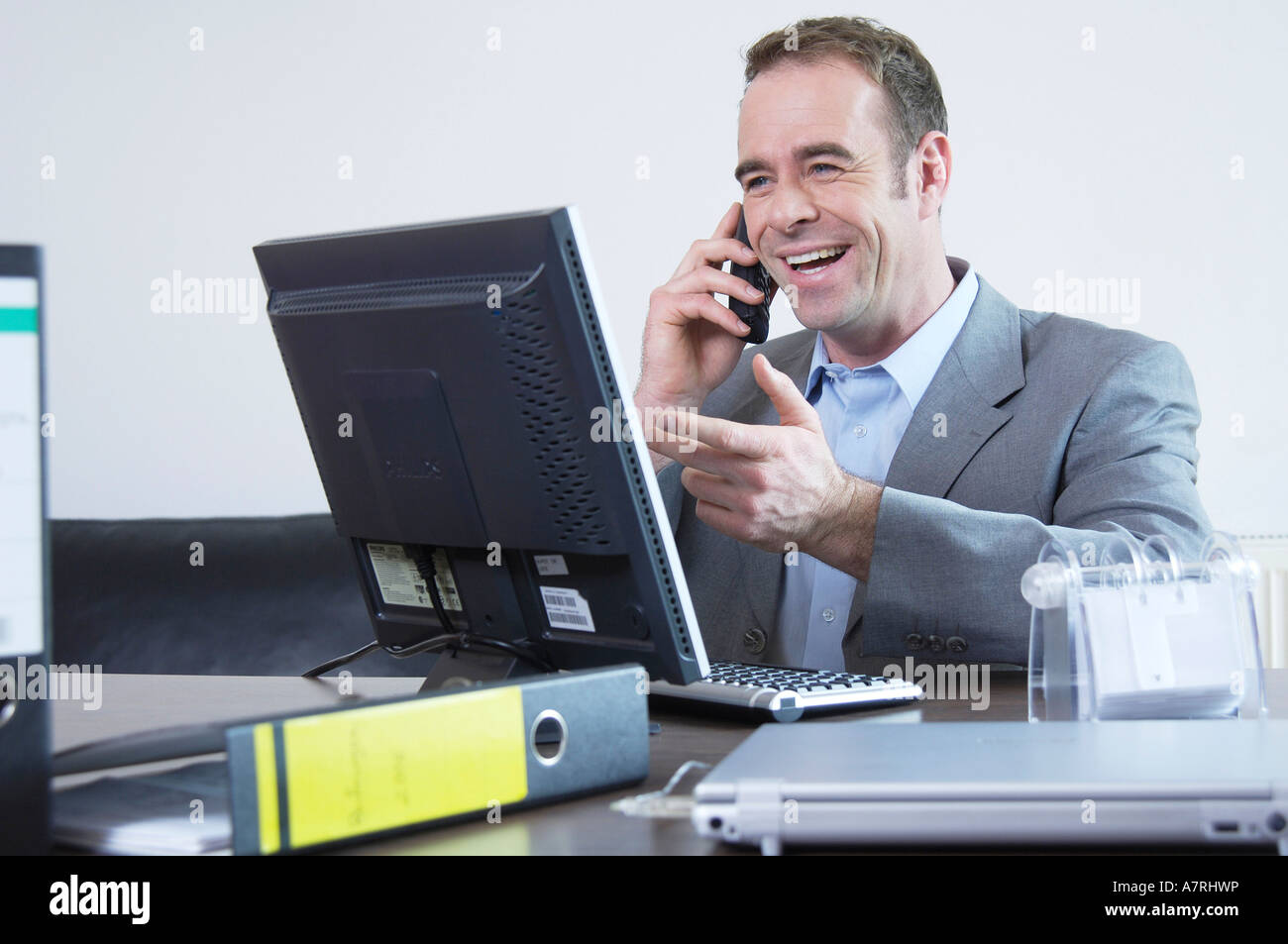 Imprenditore parlando al telefono cellulare e sorridente Foto Stock