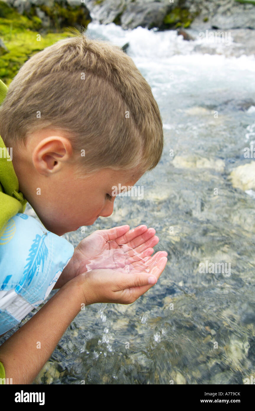 Close-up di ragazzo di bere acqua dal fiume Foto Stock