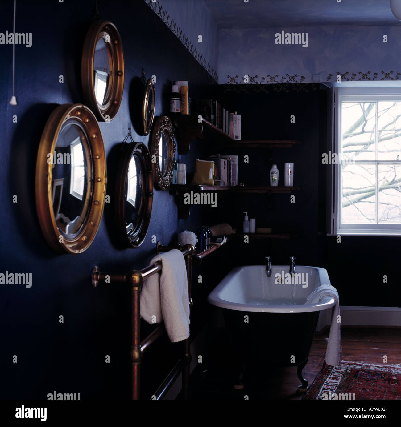 Collezione di forma ovale specchi dorati sulla parete sopra rolltop bagno nel tradizionale bagno di colore blu Foto Stock