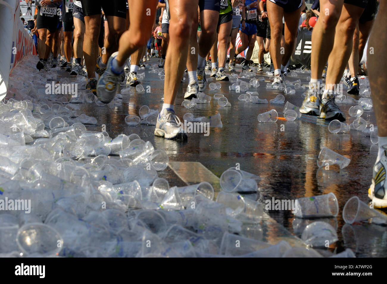 Le gambe dei corridori e tazze di plastica sul terreno con la maratona di Berlino, Berlino, Germania Foto Stock