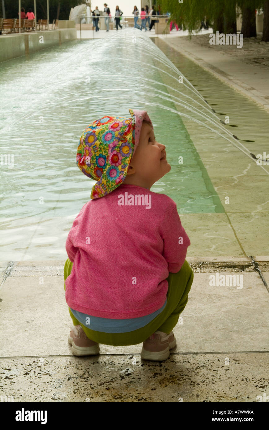 Bambina squatting da Fontana e sorridente. Foto Stock