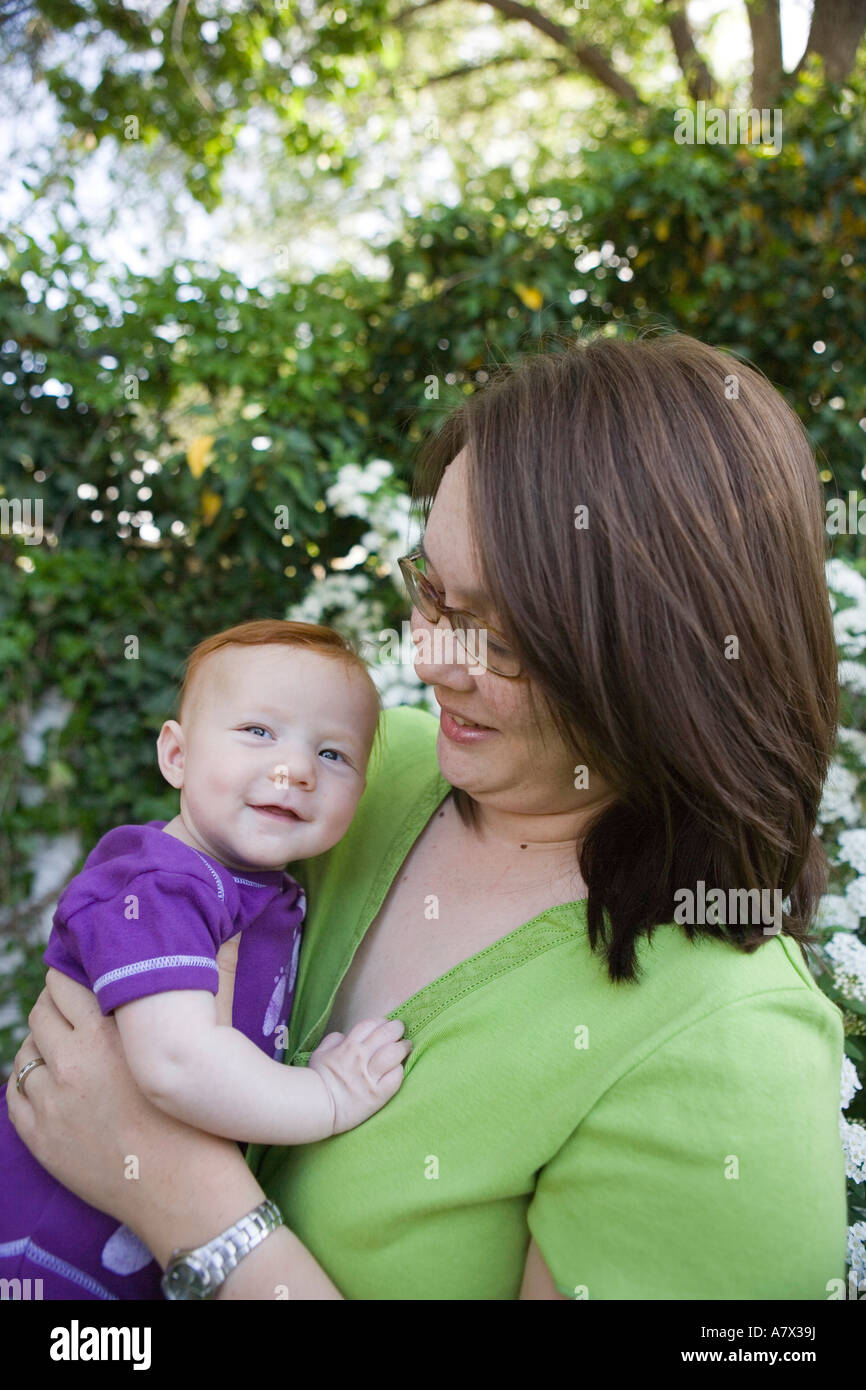 Asian madre americana detiene dai capelli rossi neonato ragazza all'aperto Foto Stock