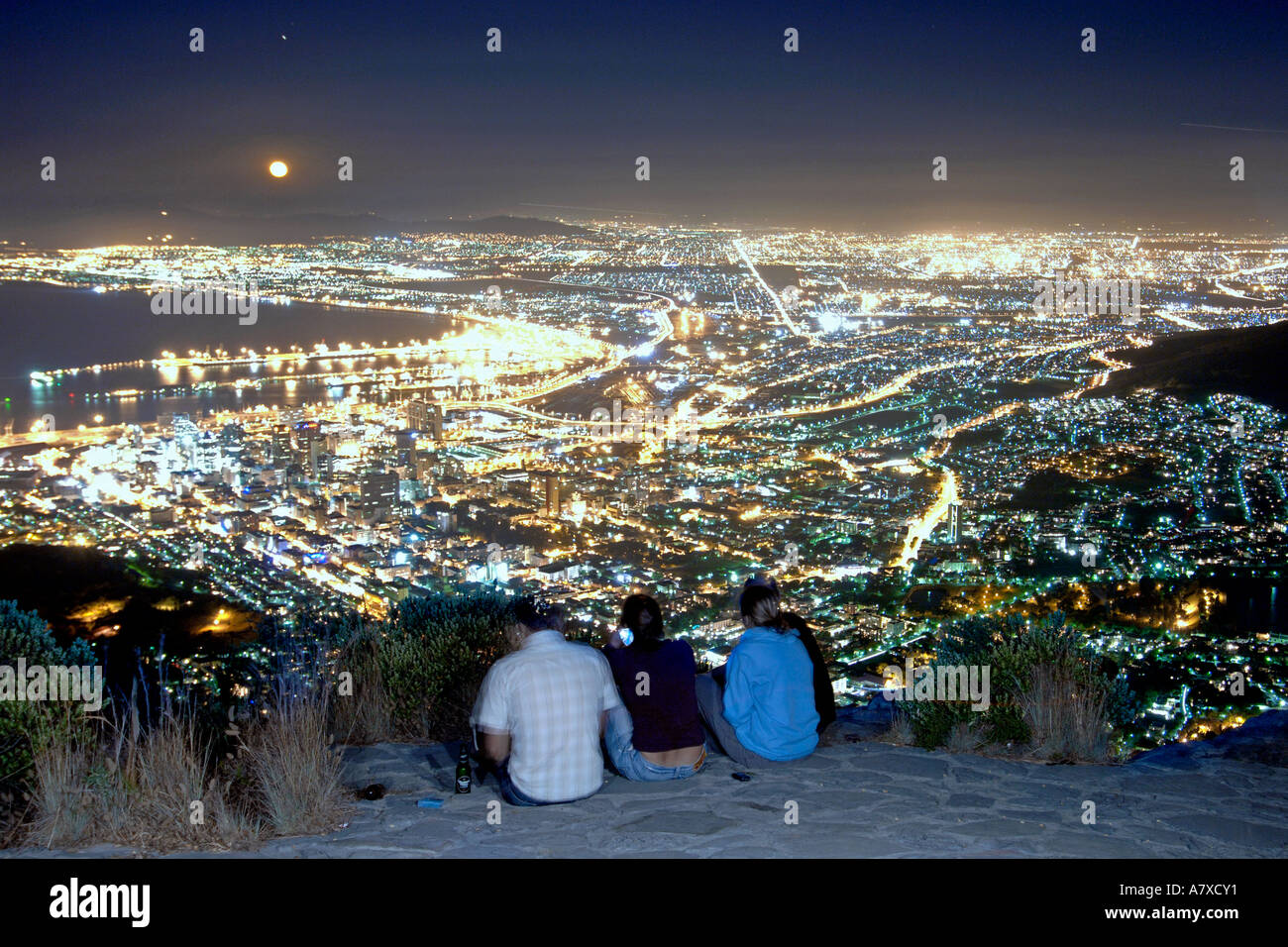 Un gruppo di persone sul vertice della testa di leone guardare la luna crescente sopra la città di Cape Town. Foto Stock