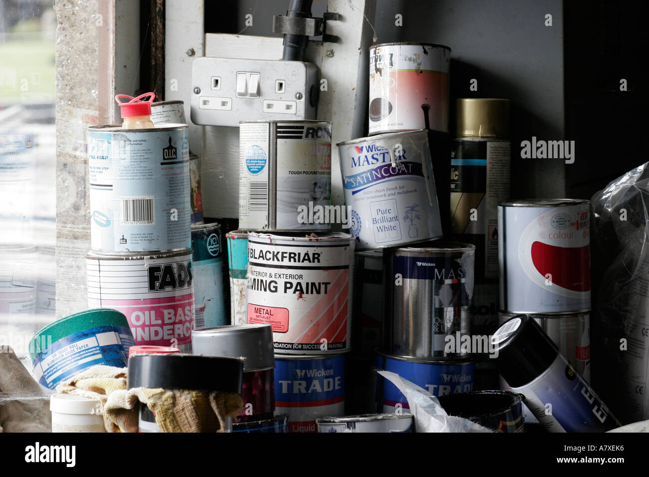 Pila di vecchi barattoli di vernice all'interno di un capannone finestra Foto Stock
