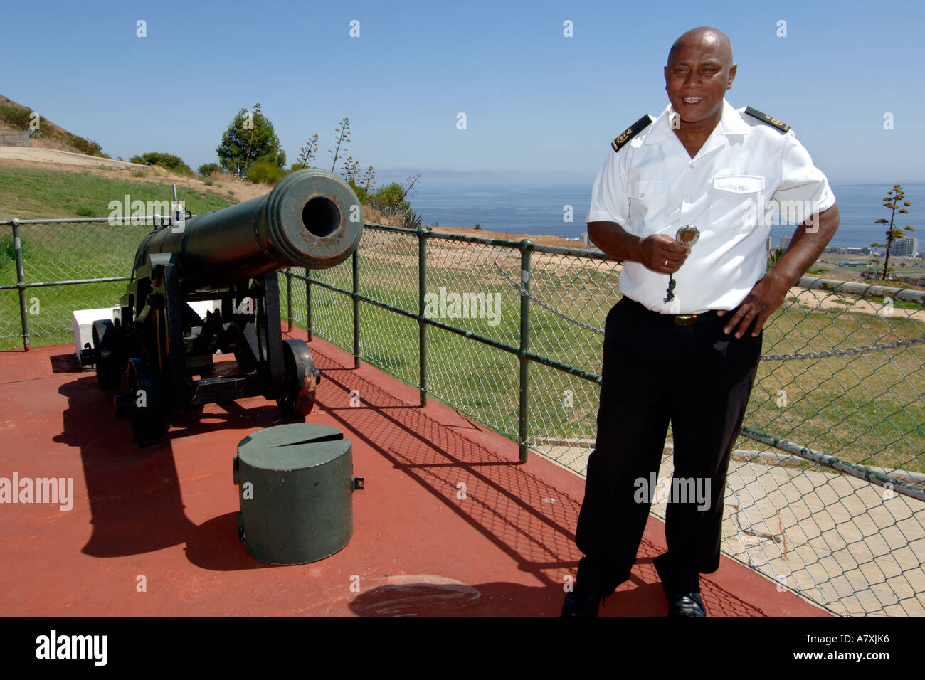 Chief Petty Officer Dudley malghe a fianco del cannone di mezzogiorno il cannone a Cape Town, Sud Africa. Foto Stock