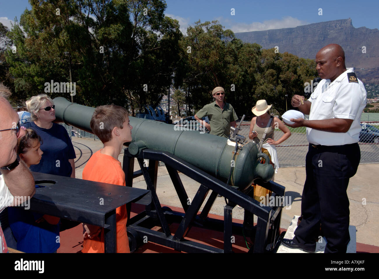 Chief Petty Officer Dudley malghe dando esplicativo parlare a fianco del cannone di mezzogiorno il cannone a Cape Town, Sud Africa. Foto Stock