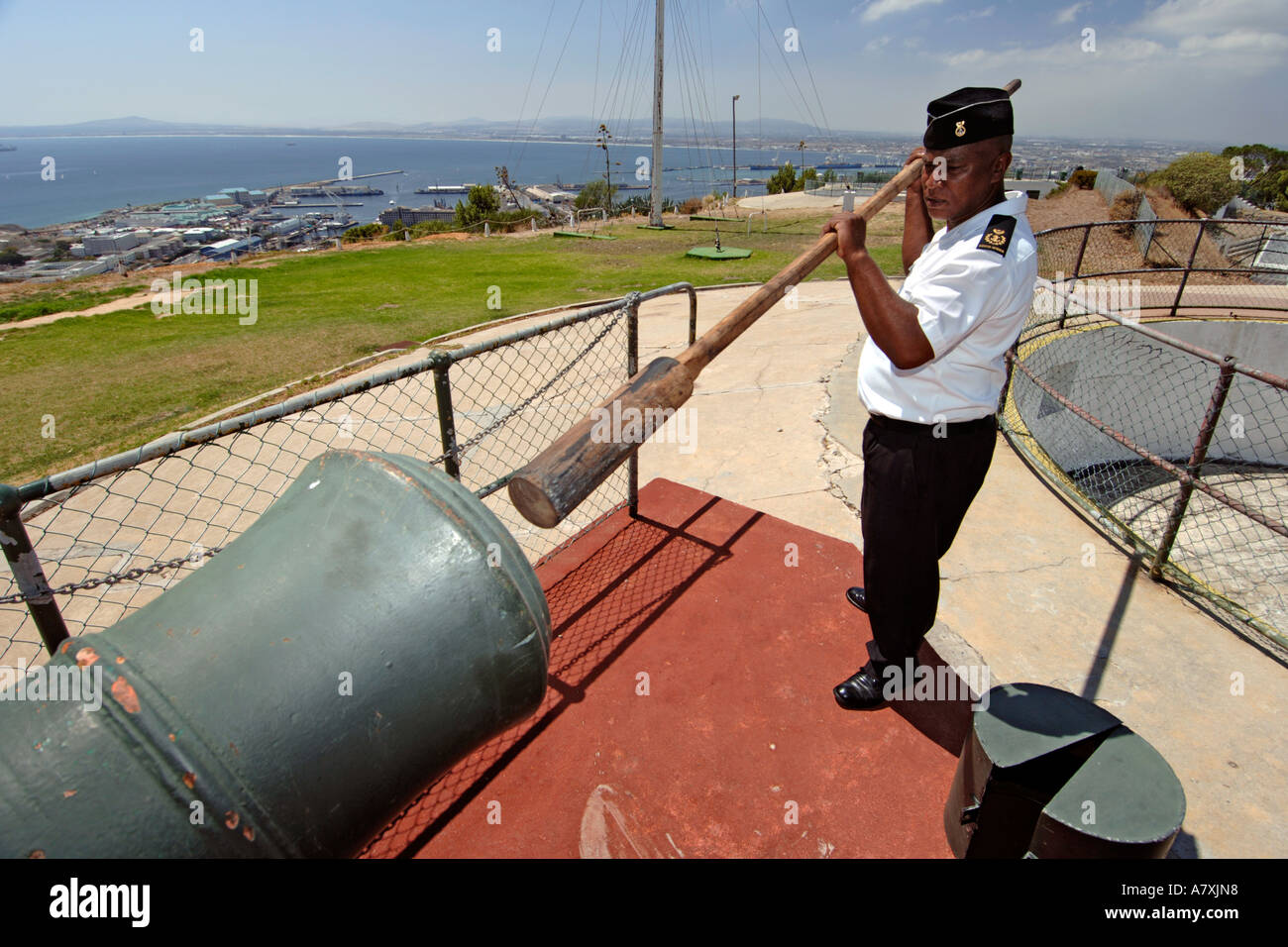 Chief Petty Officer Dudley malghe usando un cilindro di legno asta per spingere la carica nel muso del cannone di mezzogiorno il cannone a Cape Town. Foto Stock