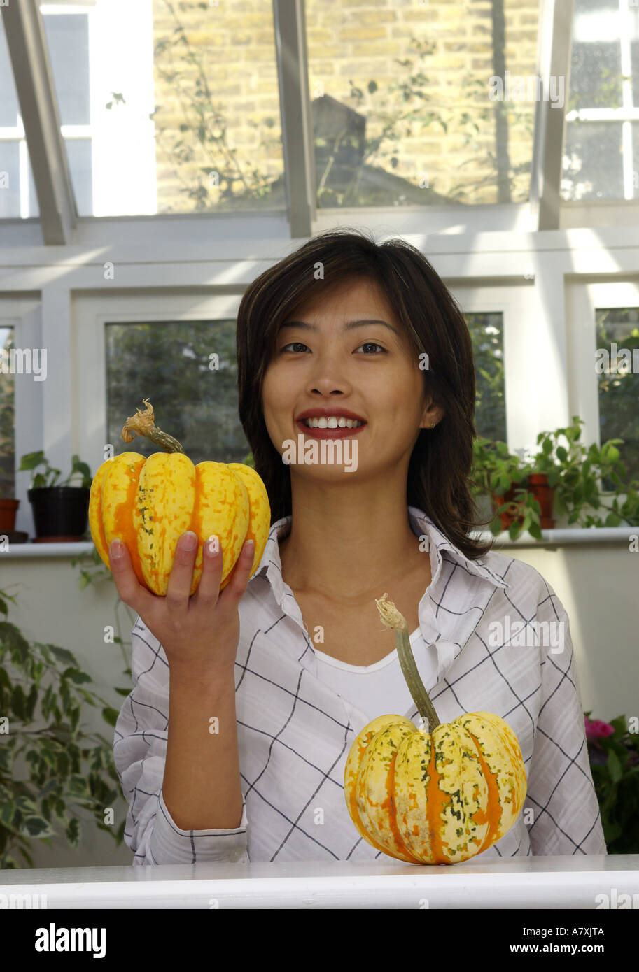 Una donna è in possesso di una zucca maturano in un conservatorio o green house Foto Stock
