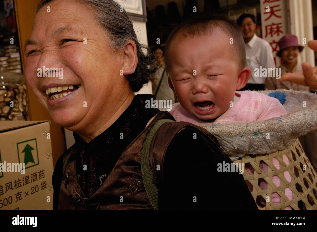 Donna con bambino nel cestello. Kunming mercato medicinali. Kunming. Nella provincia dello Yunnan. Cina Foto Stock