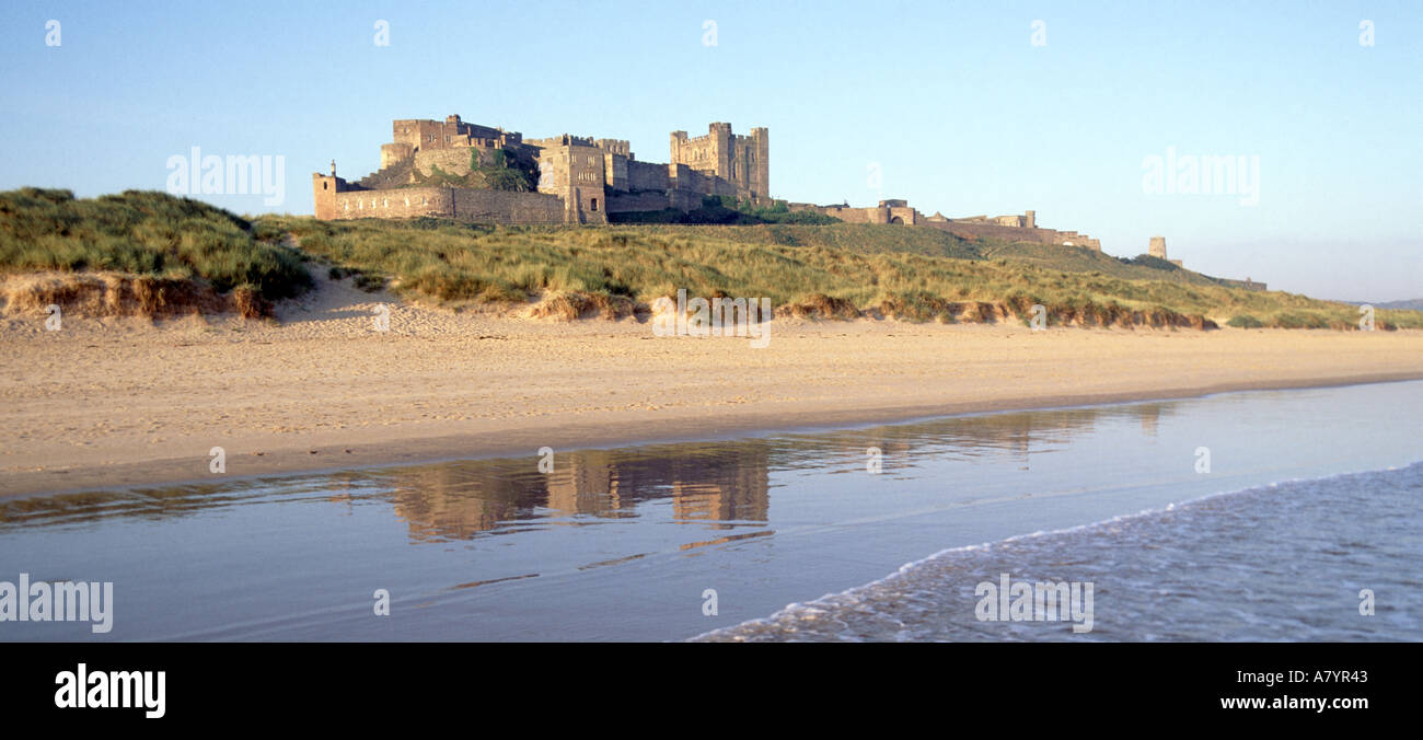 Storico litorale Bamburgh Castle paesaggio riflesso in spiaggia sabbiosa marea acqua & dune di sabbia panoramica Northumberland Mare del Nord costa Inghilterra Regno Unito Foto Stock