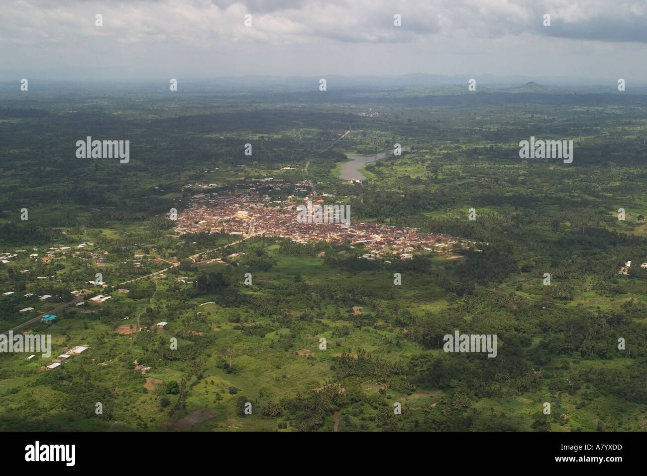 Vista aerea della piccola città in Ghana Africa Occidentale che mostra le necessarie infrastrutture, tra cui il lago con la diga e la tempesta di avvicinamento Foto Stock