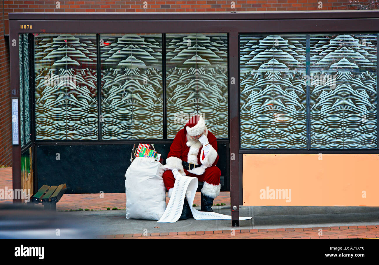 Babbo Natale legge il suo naughty e bella lista in attesa per un autobus Foto Stock