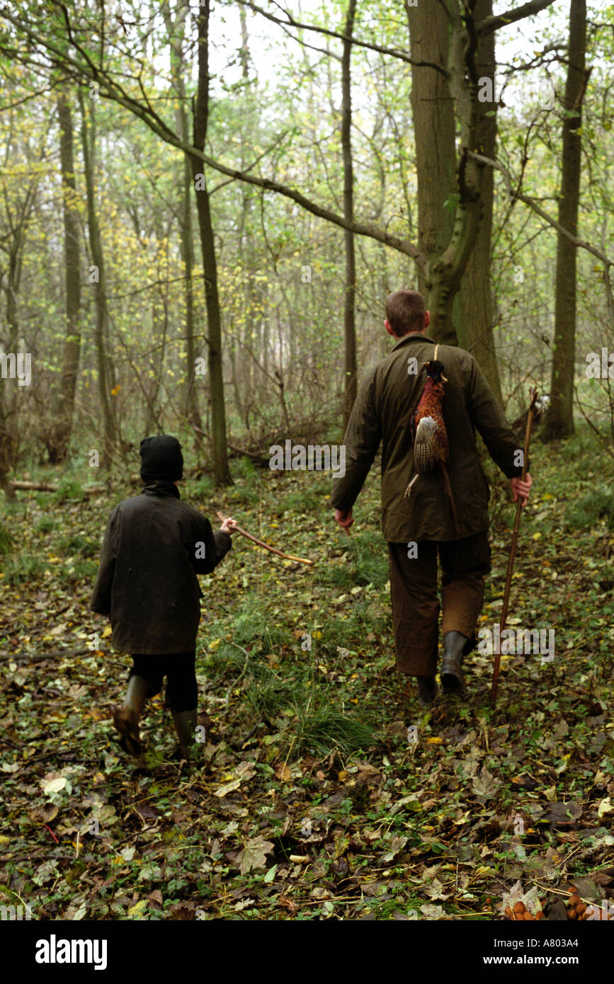 L uomo e il suo figlio a piedi nei boschi sulla Ford sparare in Cotswolds Foto Stock