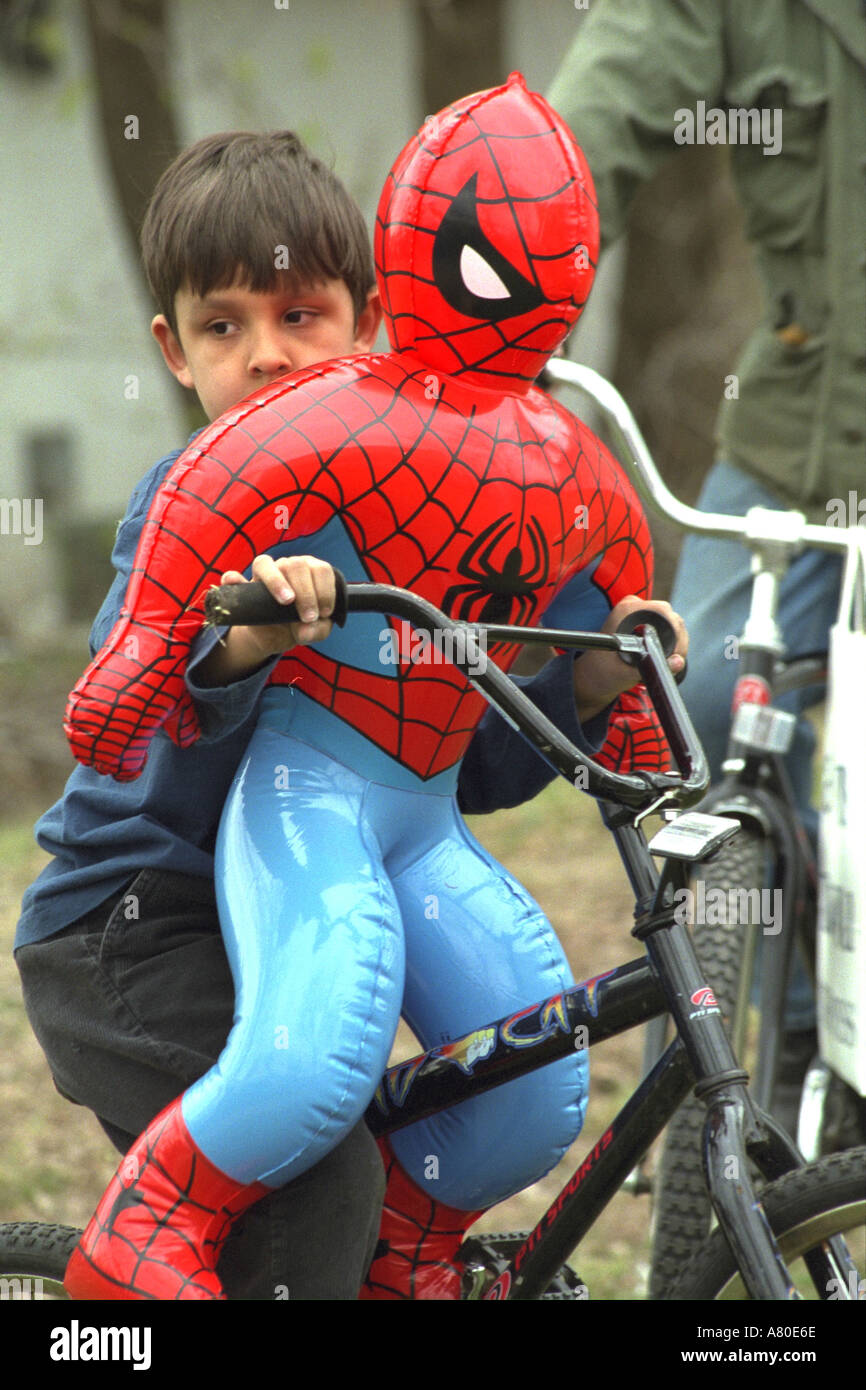 Ragazzo di 7 anni in bicicletta con Spiderman giocattolo al Cinco de Mayo festival. St Paul Minnesota USA Foto Stock