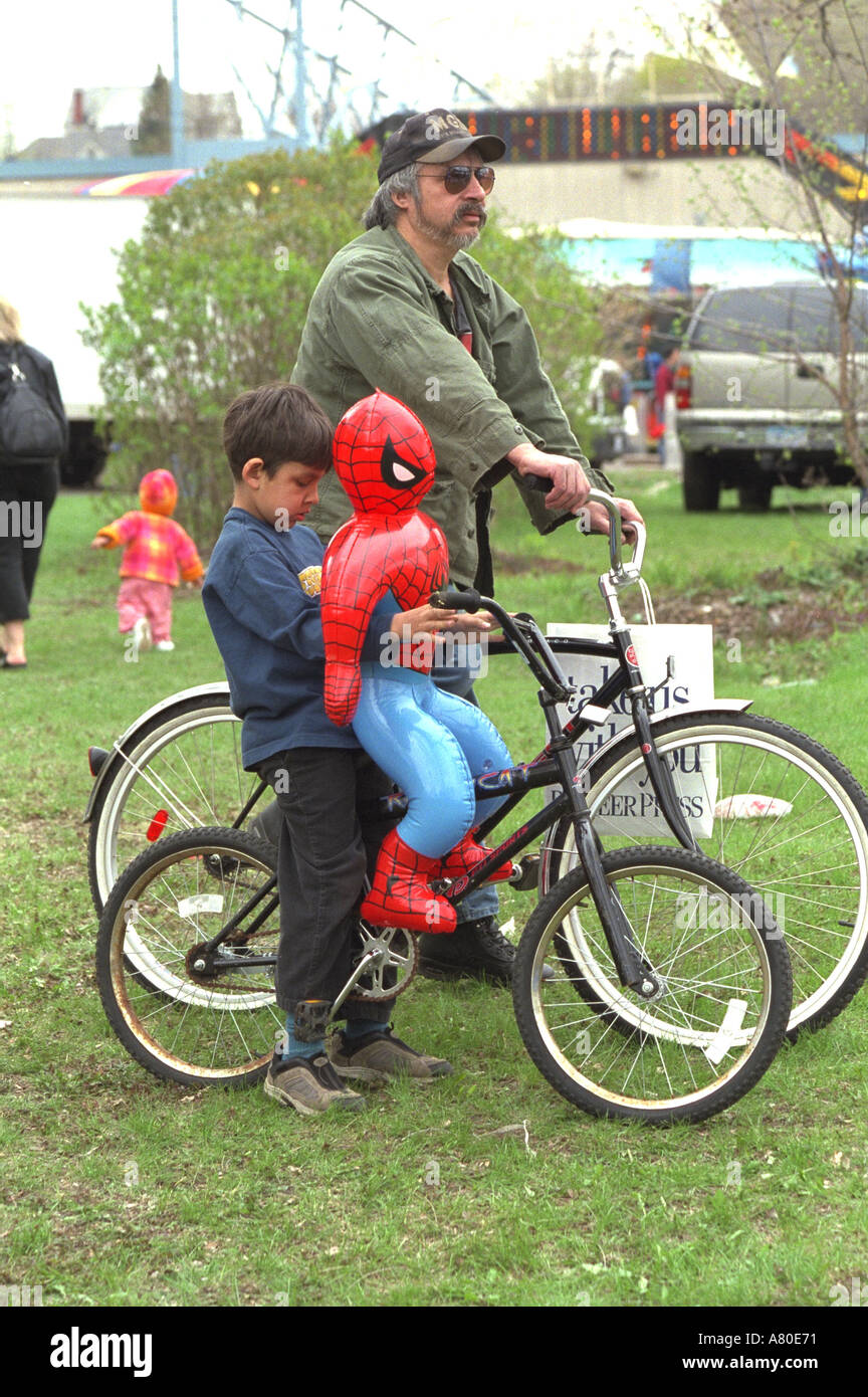 Papà e figlio di biciclette con Spiderman giocattolo al Cinco de Mayo. St Paul Minnesota USA Foto Stock