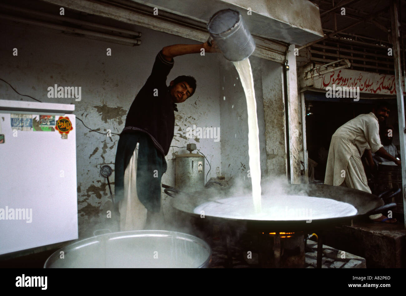 Il Pakistan a sud del Punjab uomo Bahawalpur versando il latte caldo in karahi Foto Stock