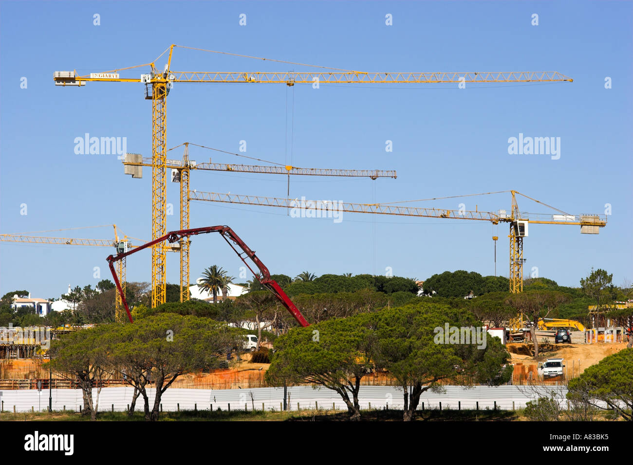 Tall gru su un sito di costruzione la costruzione di nuove case su uno sviluppo in Algarve in Portogallo. Foto Stock