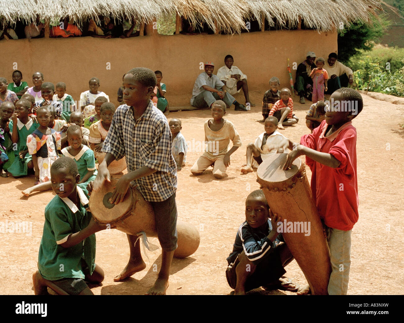 Bambini locali giocare i tamburi di bongo durante un gioco tradizionale di fronte al villaggio, Malawi, Africa orientale. Foto Stock
