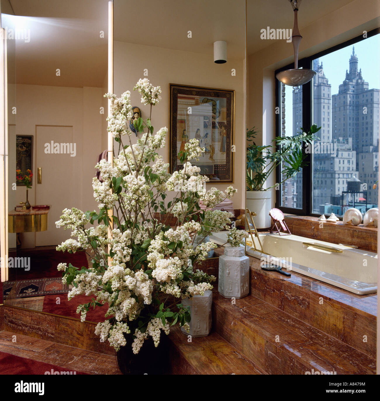 Rami alti di lilla bianco in una moderna stanza da bagno con vista di New York attraverso la finestra sopra vasca da bagno Foto Stock