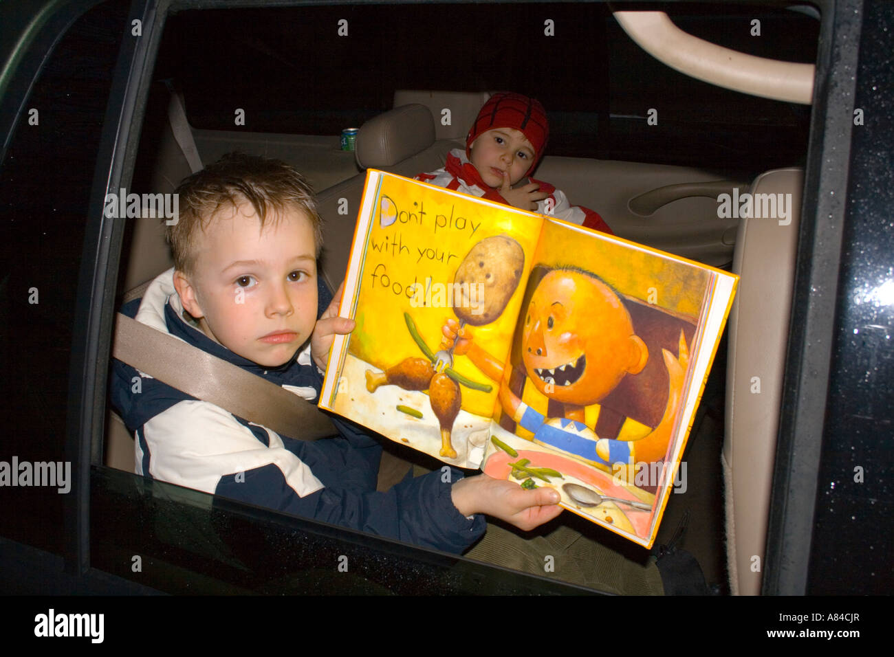 Età bambino 7 holding non giocare con il tuo libro del cibo pagina nella finestra auto. 'St Paul' Minnesota USA Foto Stock